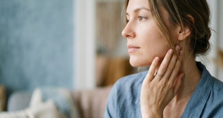 person gently touching jaw, illustrating the stress and tension link